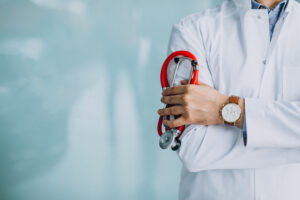 Médico com jaleco branco segurando um estetoscópio, com foco em cuidado e profissionalismo no ambiente clínico.